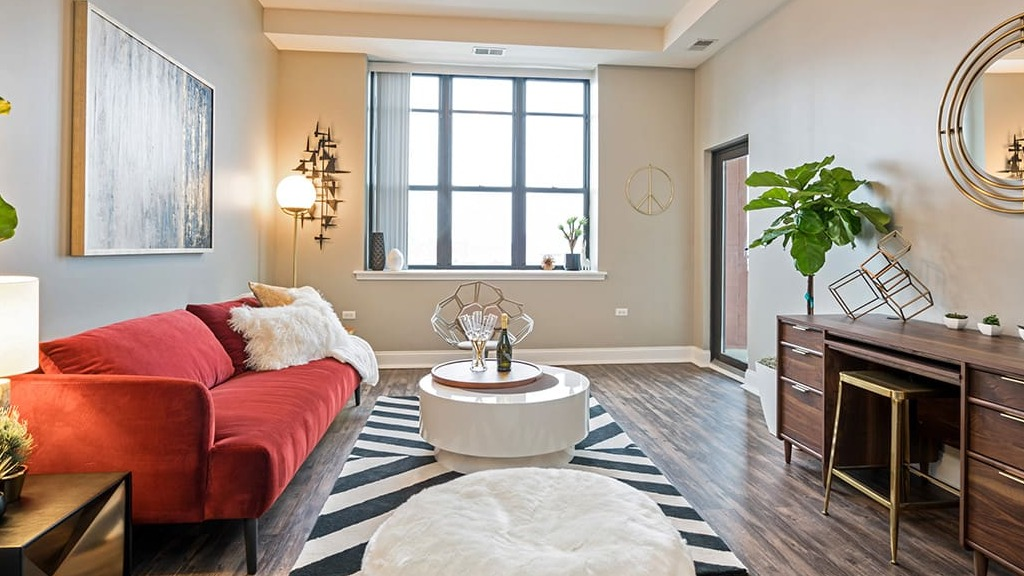 Stylish living room at Arrive South Loop apartments, with a vibrant red sofa, unique decor, and large windows offering natural light in Chicago