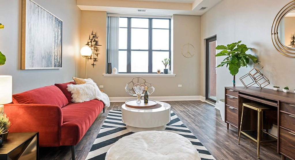 Stylish living room at Arrive South Loop apartments, with a vibrant red sofa, unique decor, and large windows offering natural light in Chicago