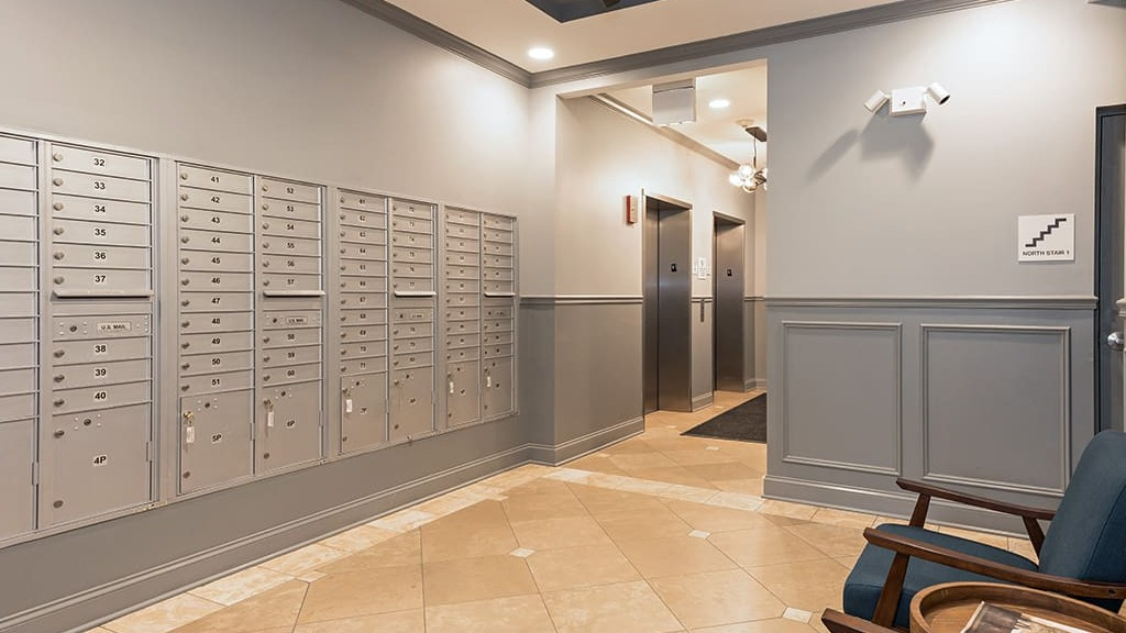 Secure and organized mailroom at Arrive South Loop apartments, with individual mailboxes and seating for residents in Chicago