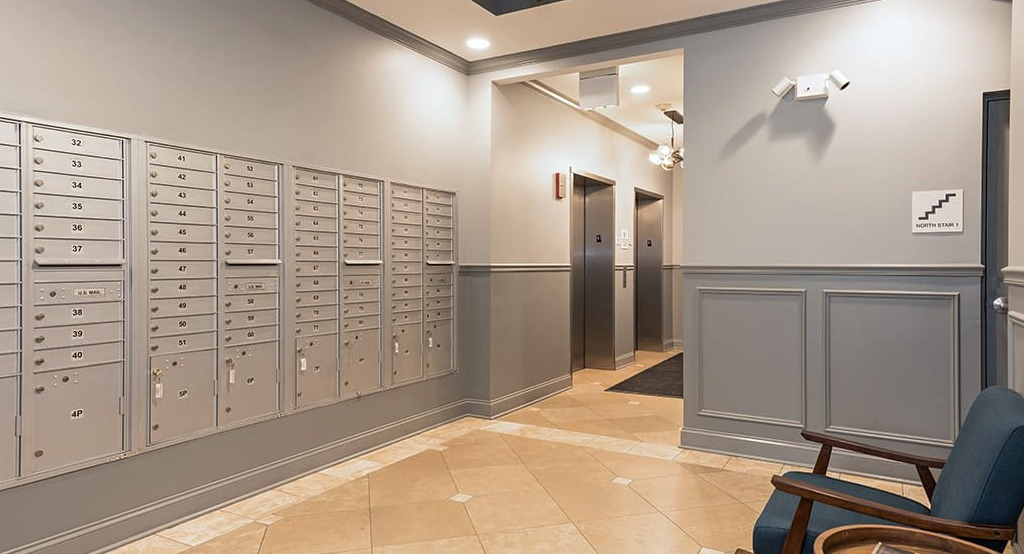 Secure and organized mailroom at Arrive South Loop apartments, with individual mailboxes and seating for residents in Chicago