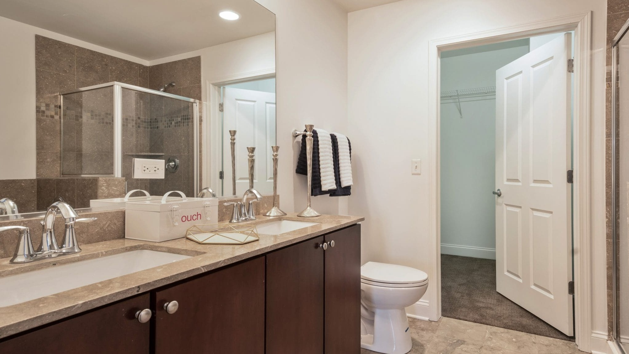 Modern bathroom at Arrive South Loop apartments, featuring a spacious double vanity, glass shower, and elegant tile work in Chicago