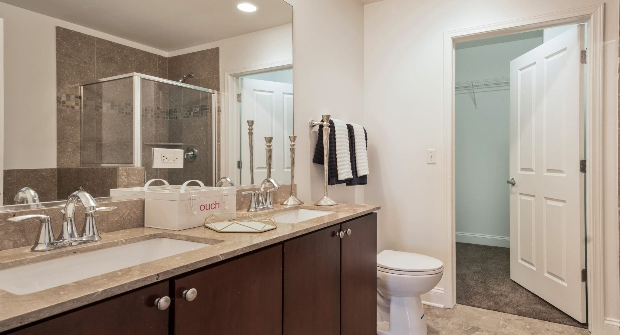 Modern bathroom at Arrive South Loop apartments, featuring a spacious double vanity, glass shower, and elegant tile work in Chicago