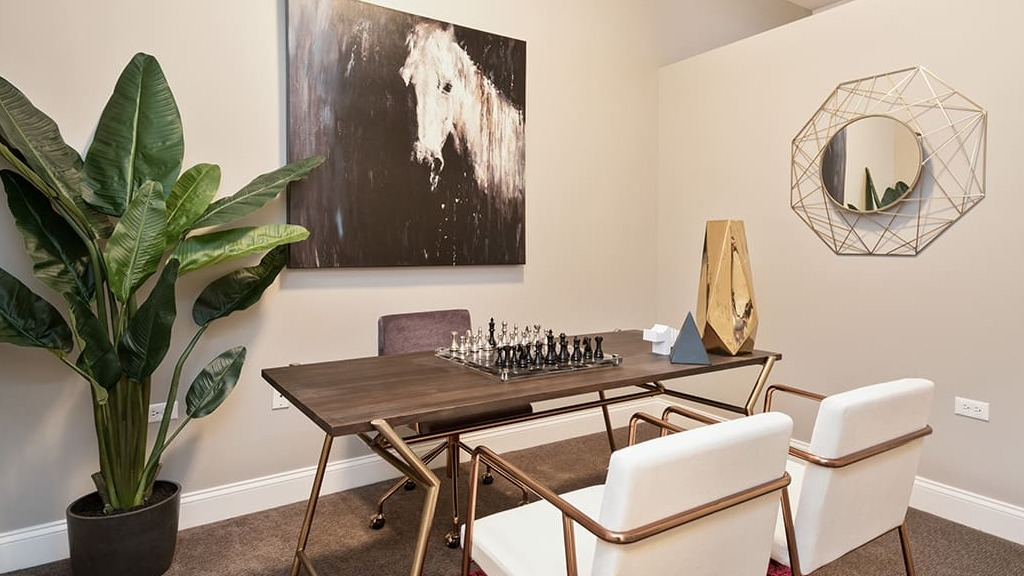 Elegant private office space at Arrive South Loop apartments, featuring a desk, comfortable chairs, and decorative art in Chicago