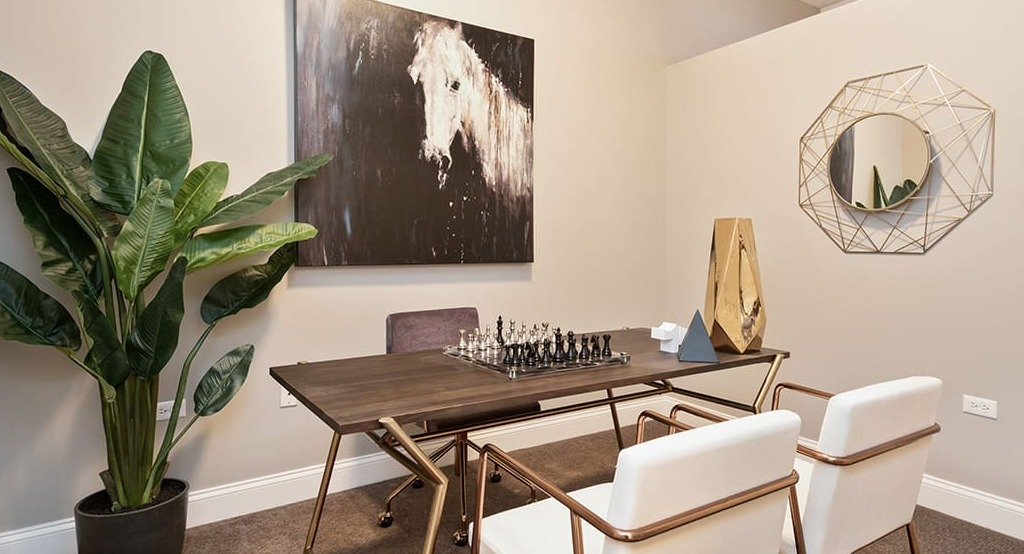Elegant private office space at Arrive South Loop apartments, featuring a desk, comfortable chairs, and decorative art in Chicago