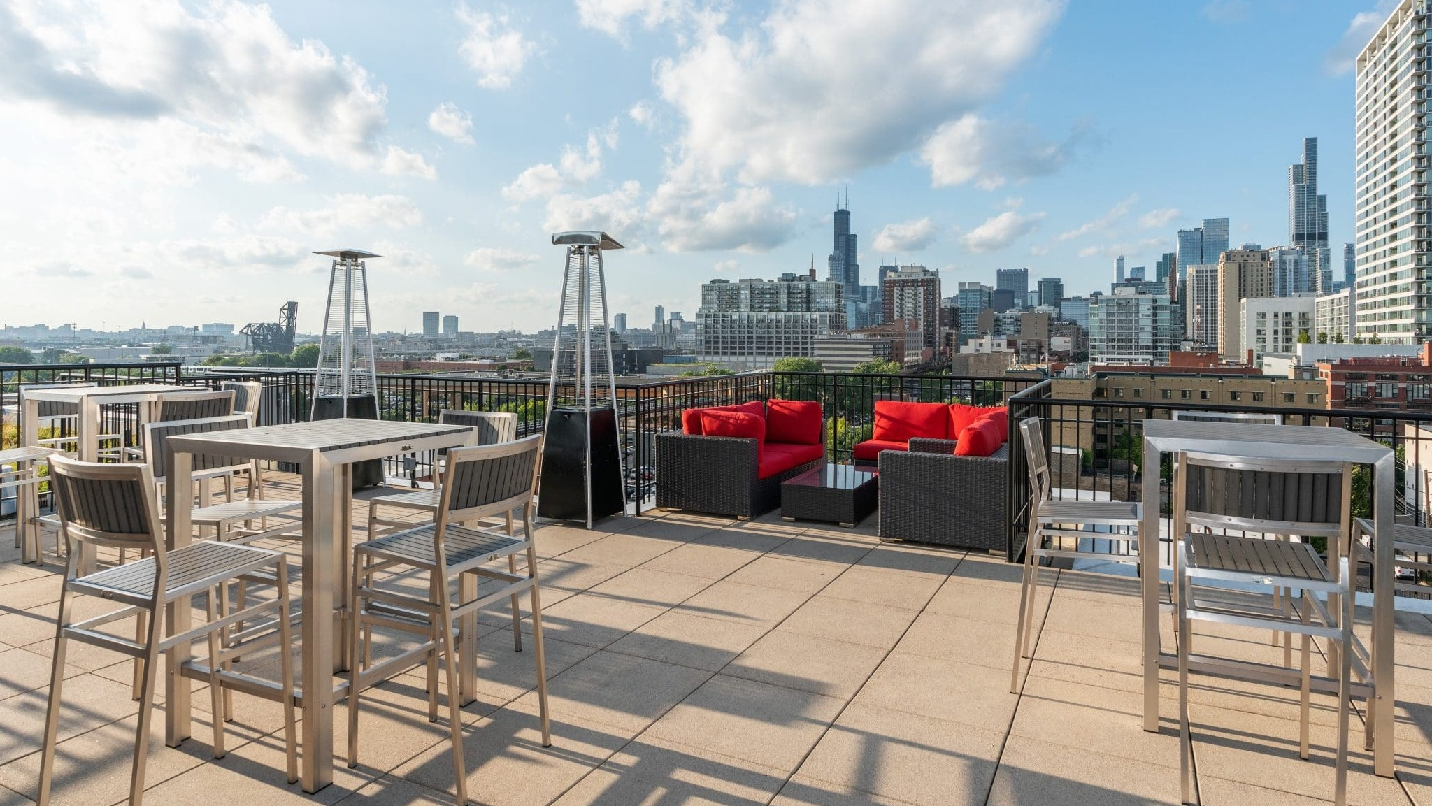 Spacious rooftop lounge at Arrive South Loop apartments with various seating options, fire pits, and expansive city views in Chicago