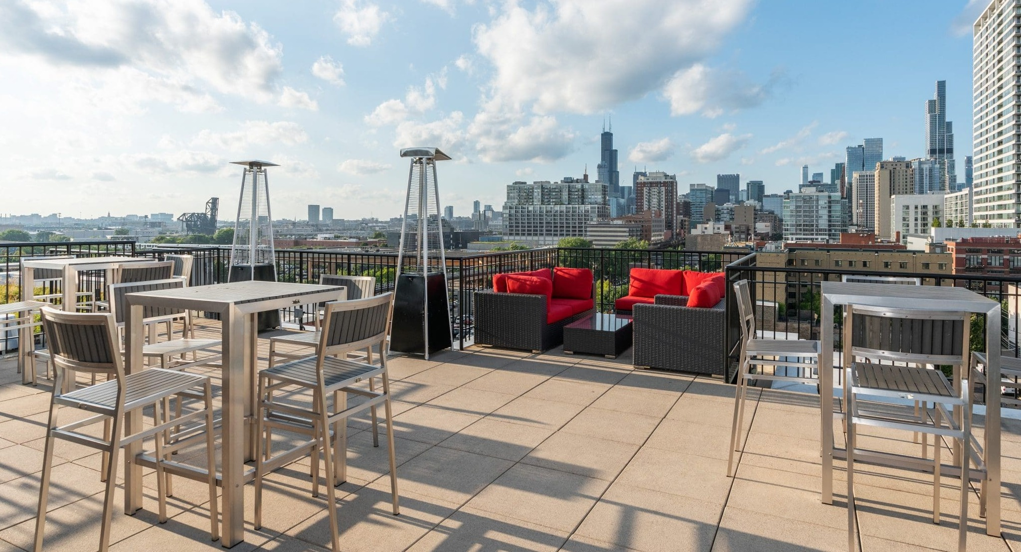 Spacious rooftop lounge at Arrive South Loop apartments with various seating options, fire pits, and expansive city views in Chicago