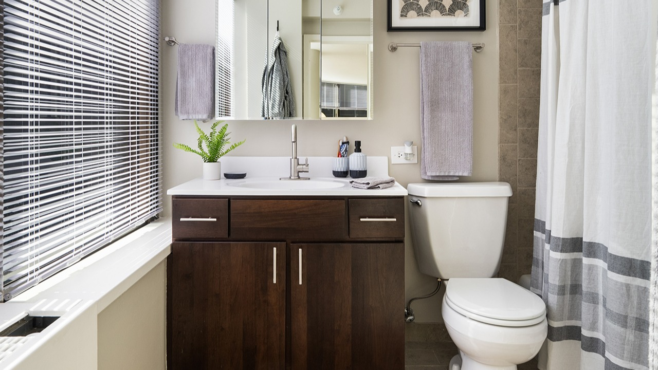 Bathroom at Arrive Streeterville with a dark wood vanity, modern sink, and large window with natural light