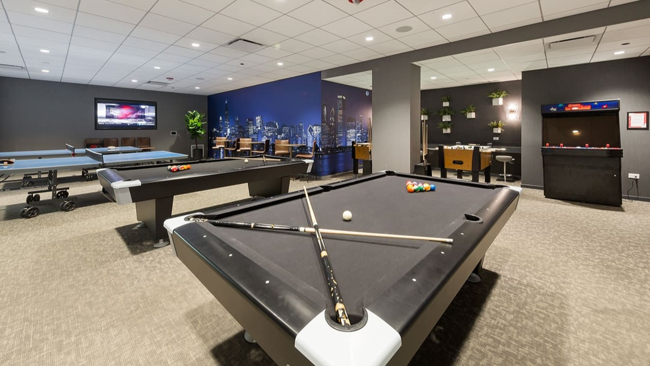 Exciting game room at Arrive Streeterville with pool tables, a ping pong table, and arcade games