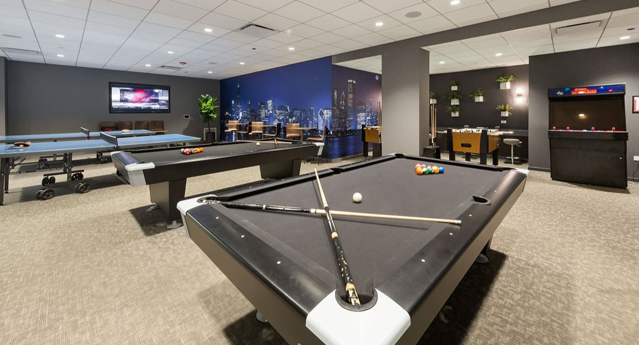 Exciting game room at Arrive Streeterville with pool tables, a ping pong table, and arcade games