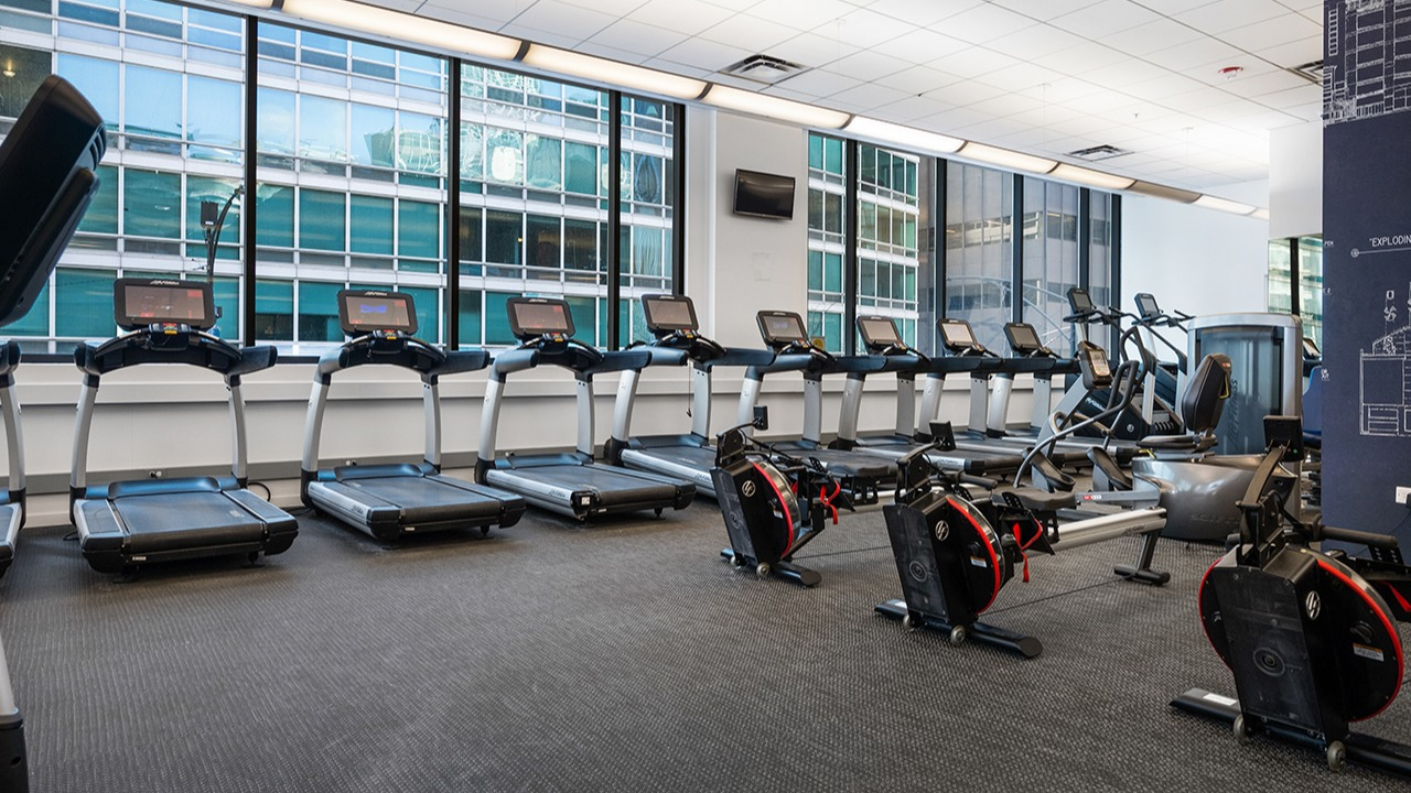 Modern gym at Arrive Streeterville featuring rows of treadmills, ellipticals, and stationary bikes