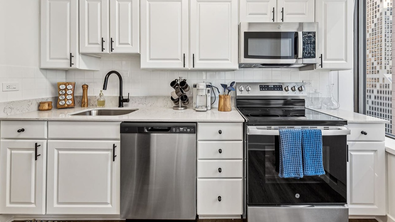 Modern kitchen at Arrive Streeterville with white shaker cabinets, stainless steel appliances, and city views