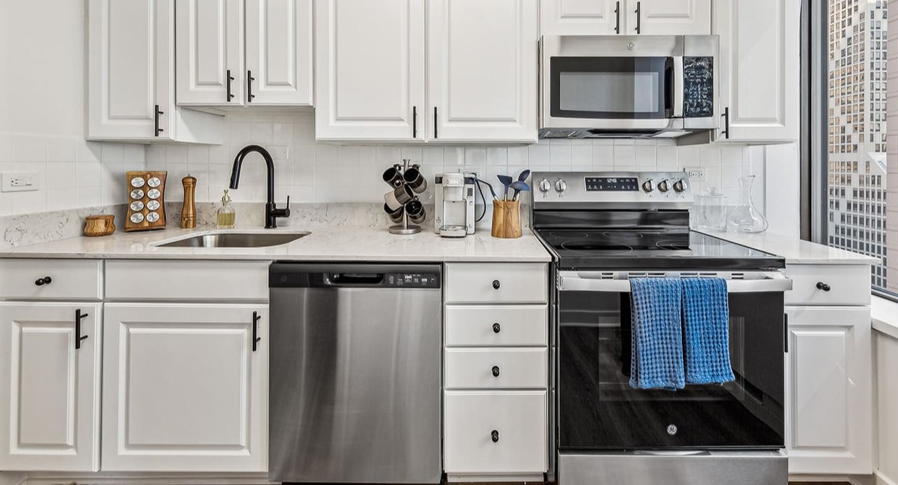Modern kitchen at Arrive Streeterville with white shaker cabinets, stainless steel appliances, and city views