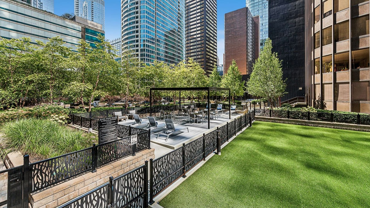 Beautiful outdoor courtyard at Arrive Streeterville with lush green lawn, seating areas, and city surroundings