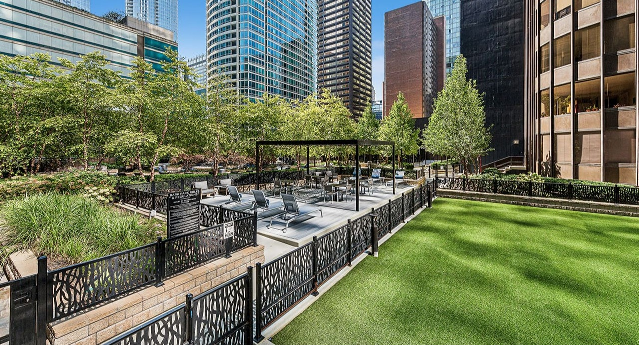 Beautiful outdoor courtyard at Arrive Streeterville with lush green lawn, seating areas, and city surroundings