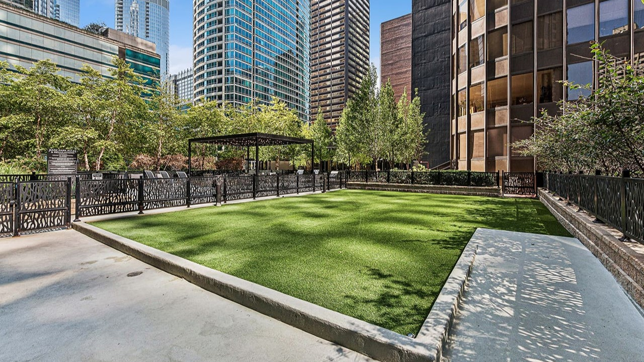 Inviting outdoor patio at Arrive Streeterville with a manicured lawn, shaded seating, and city views