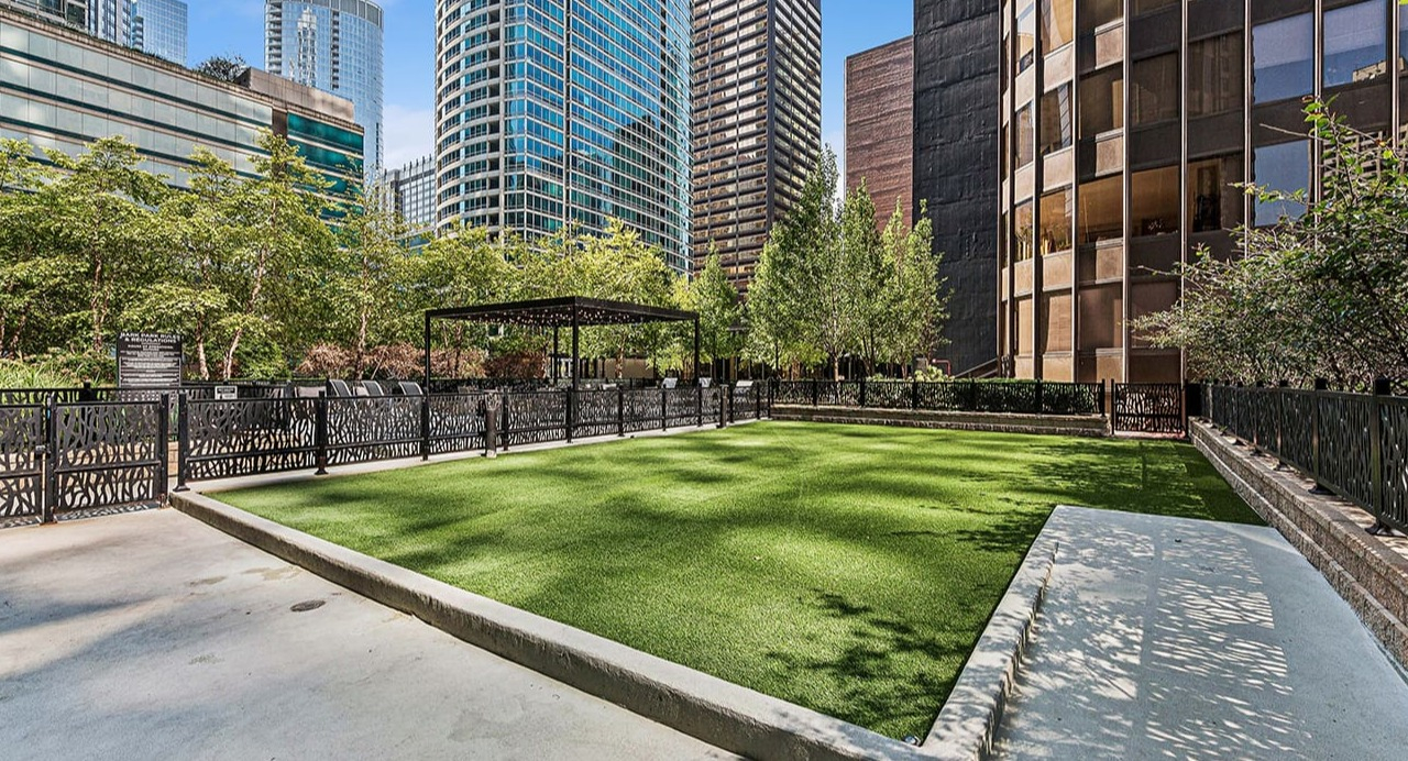 Inviting outdoor patio at Arrive Streeterville with a manicured lawn, shaded seating, and city views