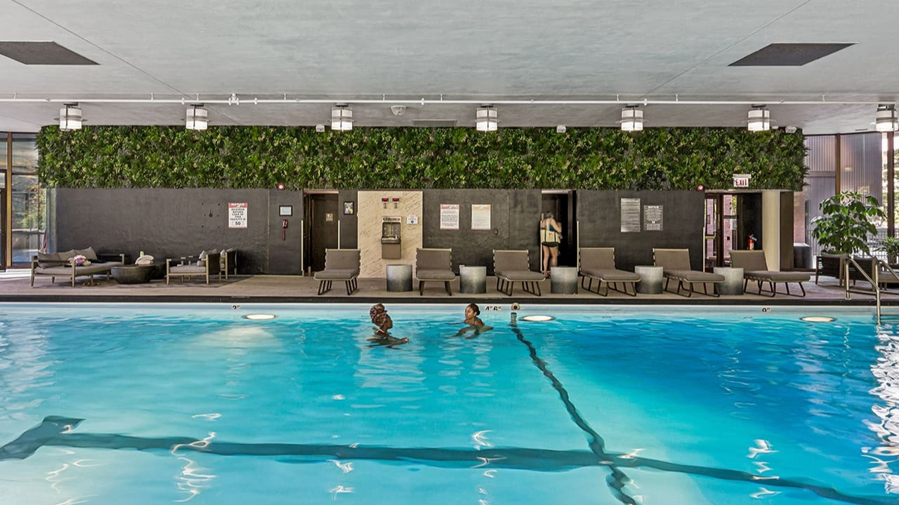 Indoor swimming pool and lounge area at Arrive Streeterville with comfortable seating and a green wall
