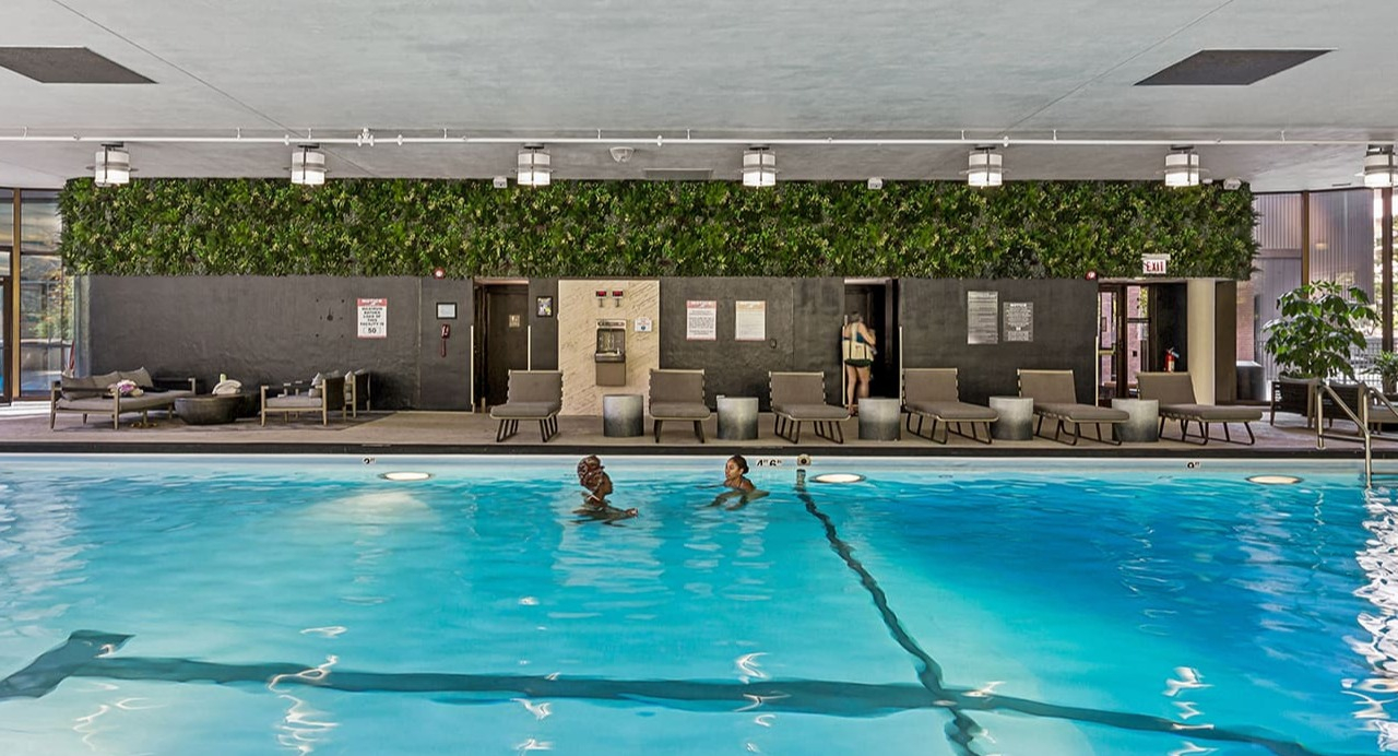 Indoor swimming pool and lounge area at Arrive Streeterville with comfortable seating and a green wall