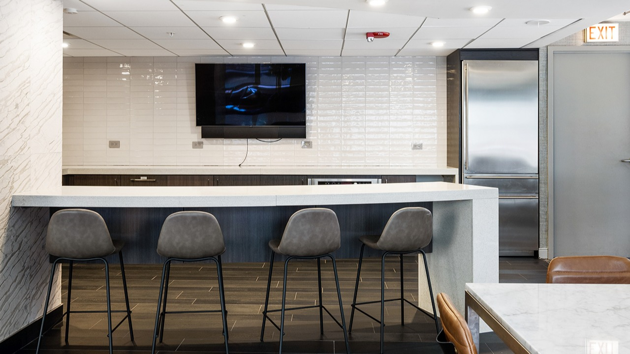 Resident lounge bar area at Arrive Streeterville with bar seating, a television, and modern finishes
