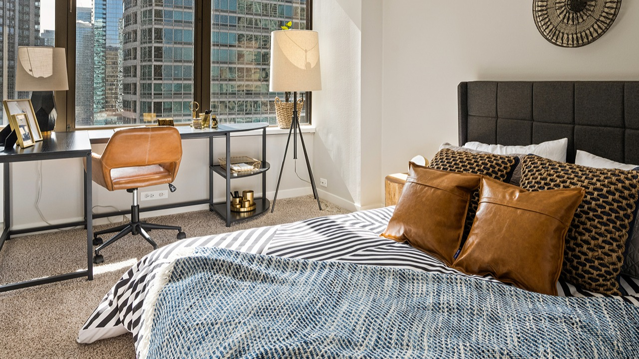 Spacious bedroom at Arrive Streeterville featuring a large bed, a work desk, and ample natural light