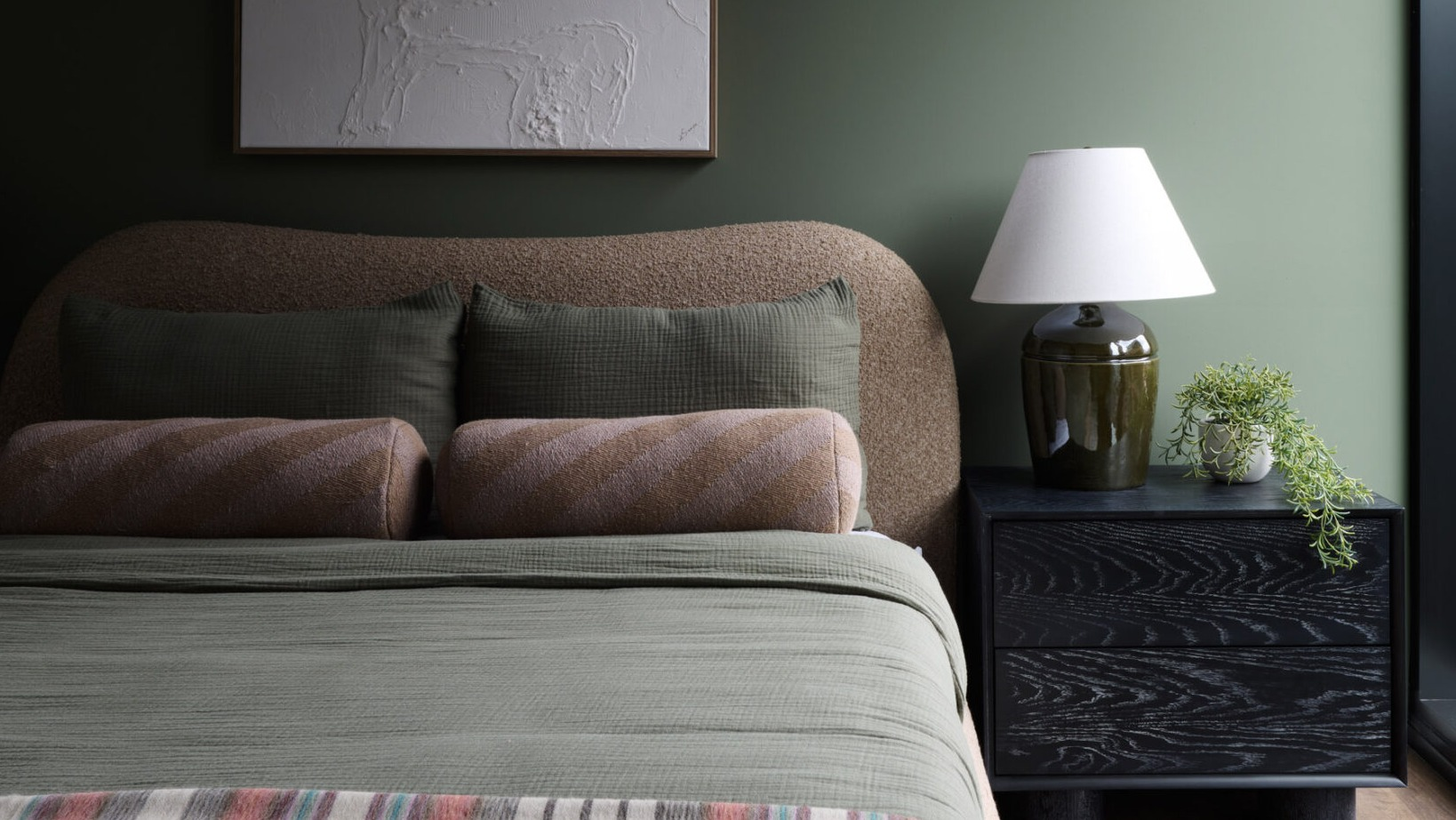Cozy bedroom in an Arthur on Aberdeen apartment in Chicago, featuring a green accent wall and large window with city views