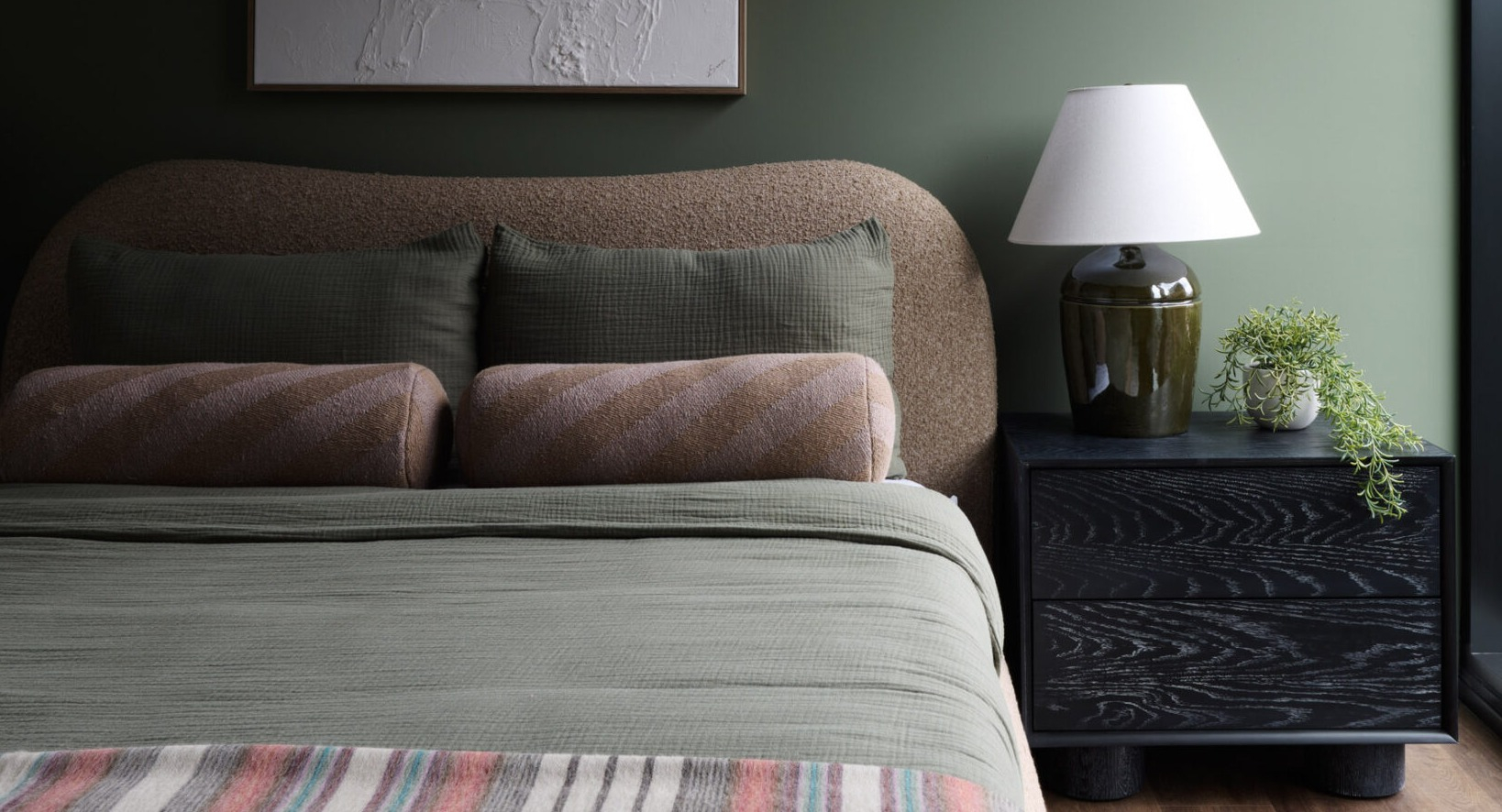 Cozy bedroom in an Arthur on Aberdeen apartment in Chicago, featuring a green accent wall and large window with city views