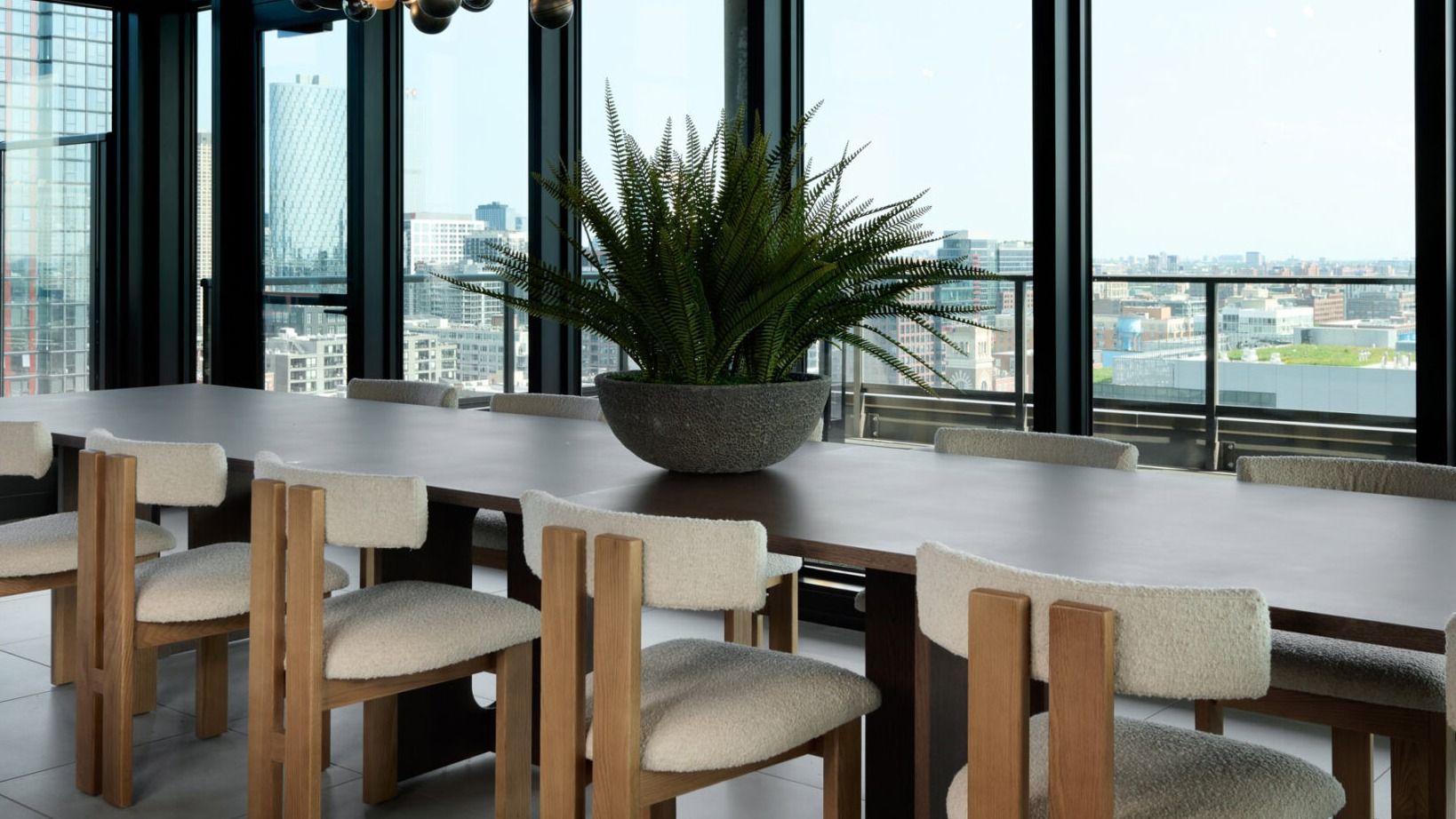 Elegant dining room at Arthur on Aberdeen in Chicago with a large table, modern chandelier, and expansive city views