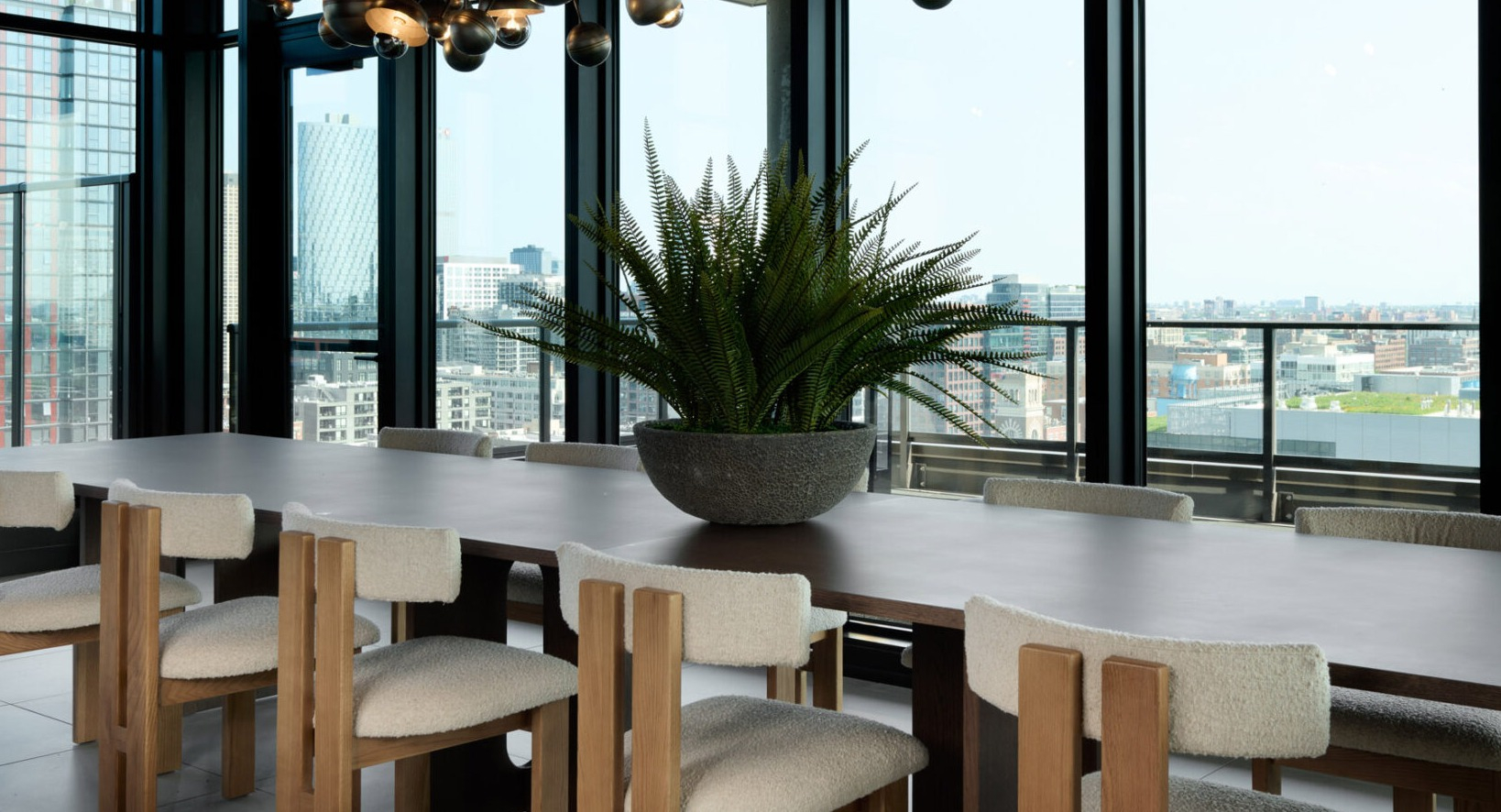 Elegant dining room at Arthur on Aberdeen in Chicago with a large table, modern chandelier, and expansive city views