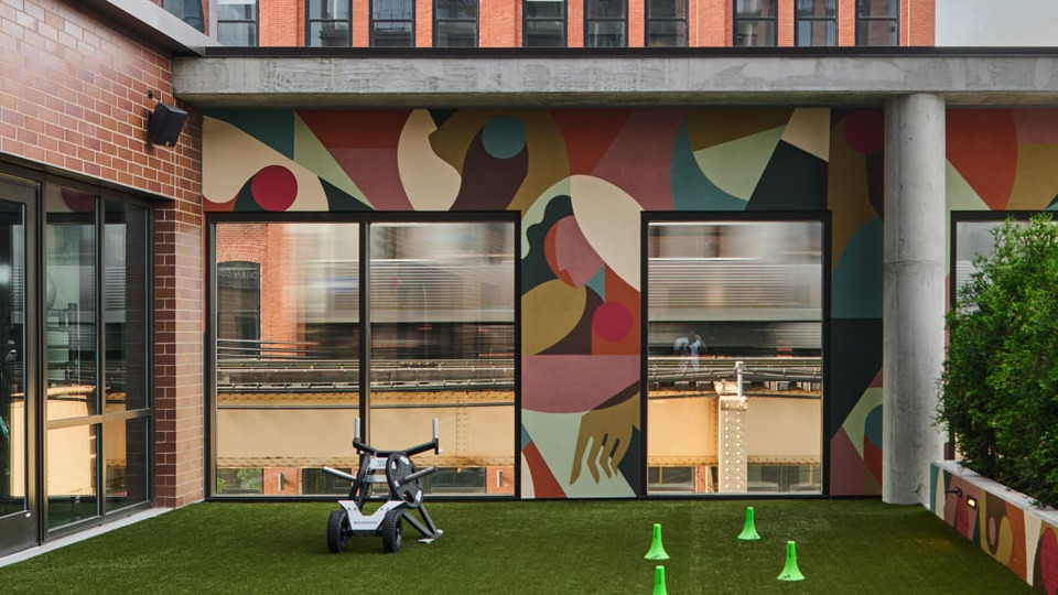 Vibrant outdoor amenity space at Arthur on Aberdeen in Chicago featuring artificial turf, a colorful mural, and skyline views