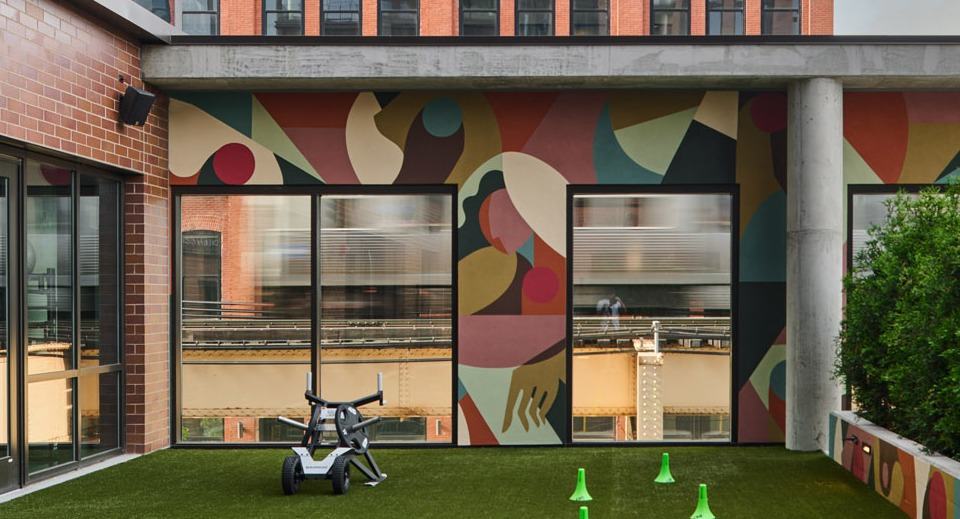 Vibrant outdoor amenity space at Arthur on Aberdeen in Chicago featuring artificial turf, a colorful mural, and skyline views