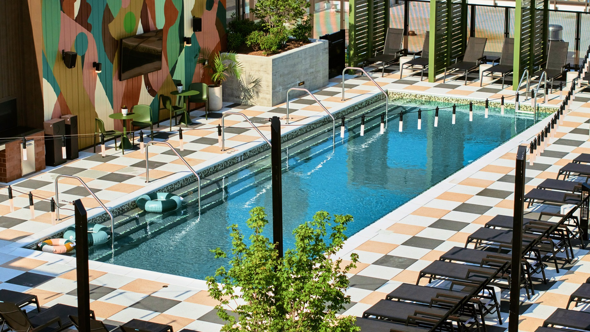 Aerial view of the vibrant rooftop pool area at Arthur on Aberdeen in Chicago, surrounded by lounge chairs and cityscapes