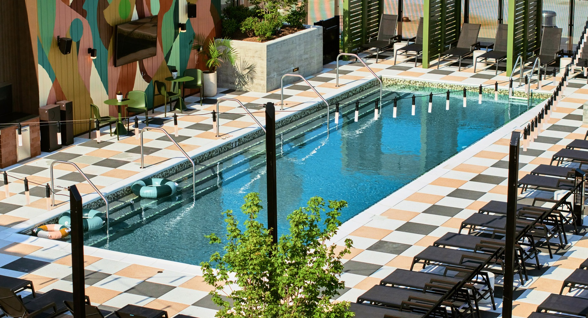Aerial view of the vibrant rooftop pool area at Arthur on Aberdeen in Chicago, surrounded by lounge chairs and cityscapes
