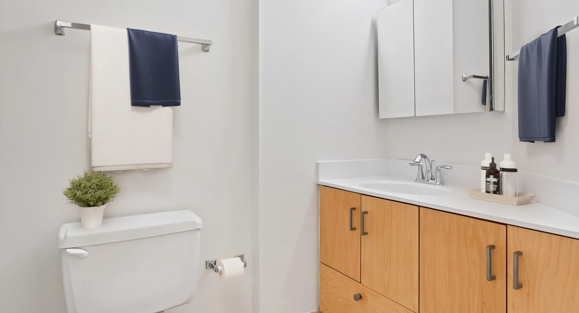 Clean and modern bathroom at Asbury Plaza in Chicago, featuring a light wood vanity and white fixtures