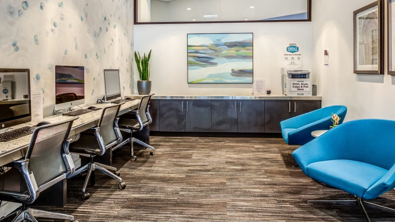 Modern business center at Asbury Plaza in Chicago with multiple computer workstations and comfortable seating