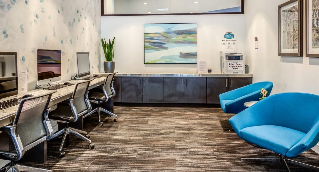 Modern business center at Asbury Plaza in Chicago with multiple computer workstations and comfortable seating