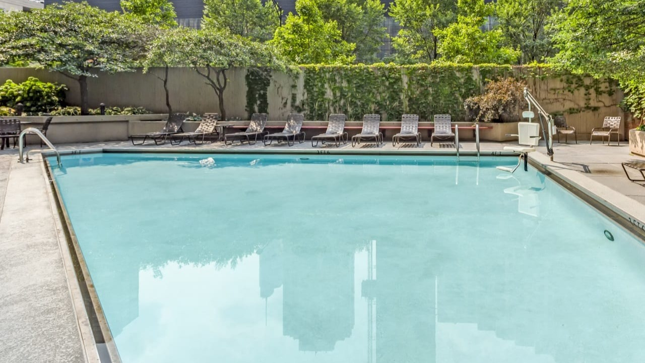 Inviting outdoor swimming pool at Asbury Plaza in Chicago, surrounded by lush greenery and city views