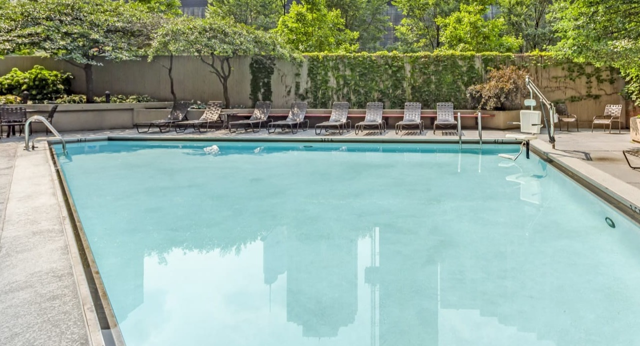 Inviting outdoor swimming pool at Asbury Plaza in Chicago, surrounded by lush greenery and city views