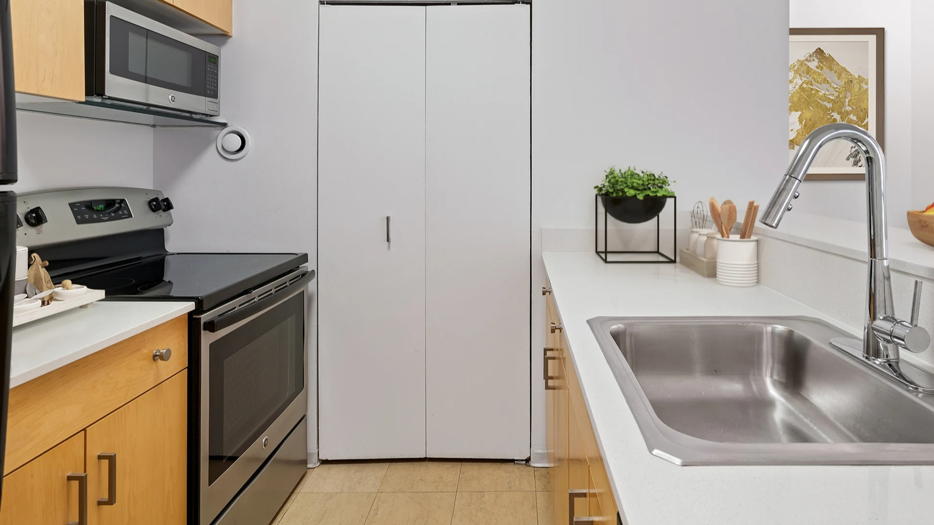 Sleek kitchen at Asbury Plaza in Chicago with light wood cabinets, stainless steel appliances, and a sink