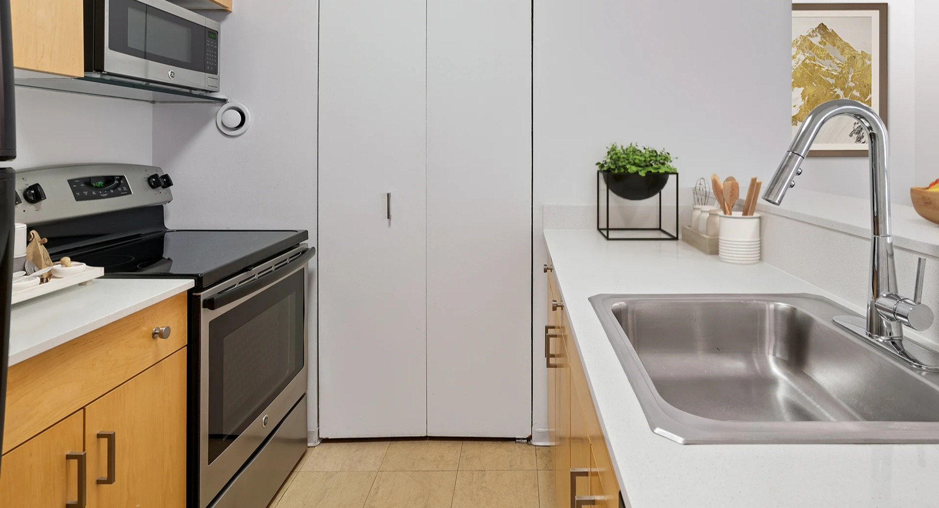 Sleek kitchen at Asbury Plaza in Chicago with light wood cabinets, stainless steel appliances, and a sink