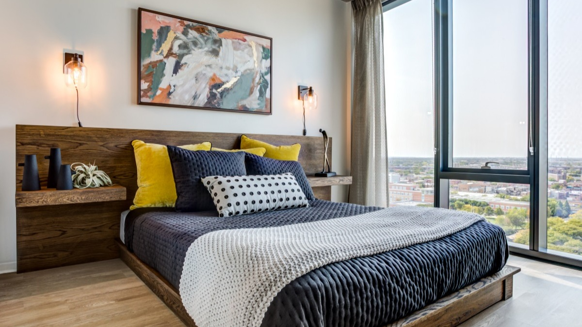Chic bedroom at Aspire Residences in Chicago, offering a comfortable bed, vibrant art, and expansive city views