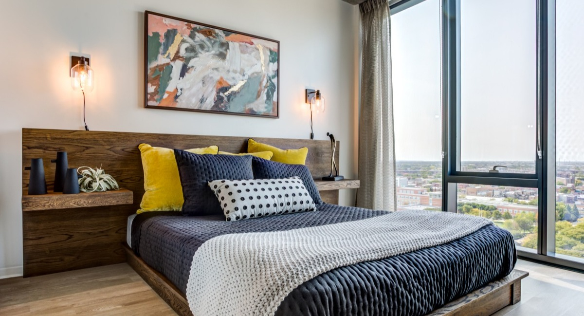 Chic bedroom at Aspire Residences in Chicago, offering a comfortable bed, vibrant art, and expansive city views