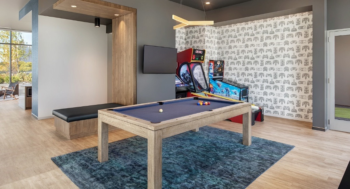 Fun game room at Aspire Residences in Chicago, featuring a pool table, arcade games, and seating