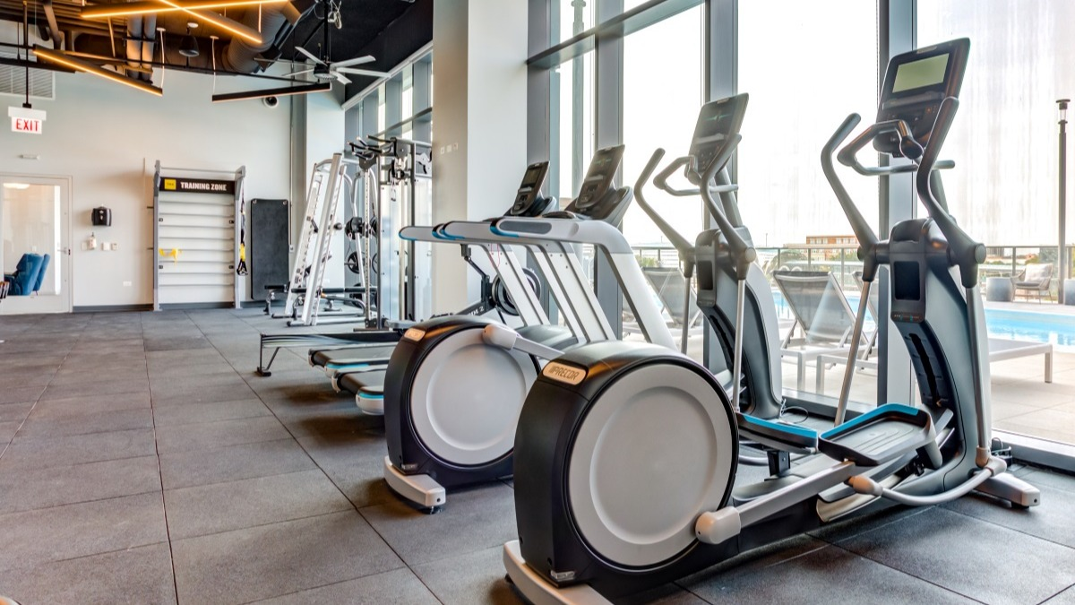 Modern fitness center at Aspire Residences in Chicago, equipped with cardio machines and city views