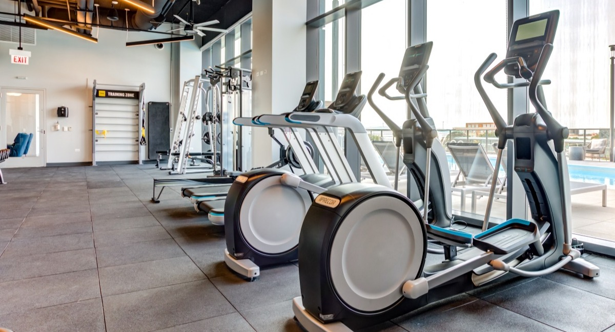Modern fitness center at Aspire Residences in Chicago, equipped with cardio machines and city views