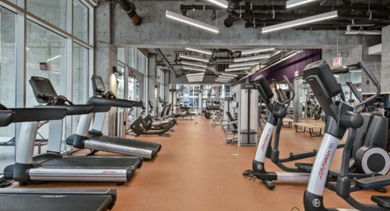 Well-equipped fitness center with rows of treadmills, ellipticals, and other exercise machines at Aston Chicago Apartments