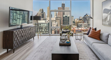 Spacious living room featuring a comfortable sofa, entertainment center, and expansive views of the Chicago skyline