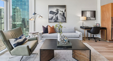 Bright living room with floor-to-ceiling windows, a comfortable armchair, and a dedicated workspace at Aston Chicago Apartments