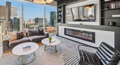 Cozy resident lounge featuring a comfortable sofa, modern fireplace, and large windows with city views at Aston Chicago Apartments