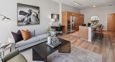 Open-concept living room and kitchen area with modern furniture, a large sofa, and a kitchen island at Aston Chicago Apartments