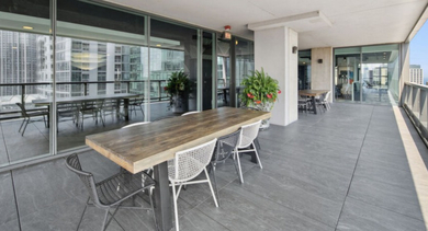 Spacious outdoor balcony with a large dining table, chairs, and cityscape views at Aston Chicago Apartments